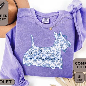 Pu&ograve; includere: Felpa viola con un disegno floreale di cane e il nome "Luna". L'illustrazione del cane &egrave; riempita con un motivo floreale blu e bianco. La felpa ha un girocollo e maniche lunghe. L'immagine include anche il testo "Super Soft" e "Comfort Colors".
