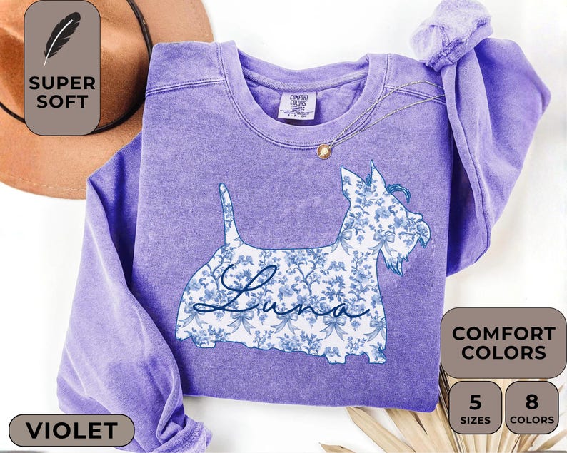 Pu&ograve; includere: Felpa viola con un disegno floreale di cane e il nome "Luna". L'illustrazione del cane &egrave; riempita con un motivo floreale blu e bianco. La felpa ha un girocollo e maniche lunghe. L'immagine include anche il testo "Super Soft" e "Comfort Colors".