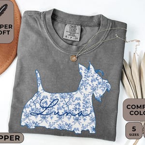 Pu&ograve; includere: T-shirt grigio Comfort Colors con un design floreale blu e bianco di un cane e il nome "Luna". La maglietta ha le parole "Super Soft" e "Pepper" stampate sopra. Disponibile in 5 taglie e 12 colori.