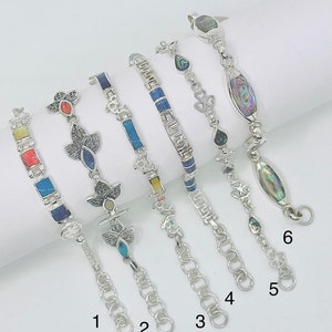 Può includere: Sei braccialetti d'argento con pietre e ciondoli colorati. I braccialetti sono numerati da 1 a 6.