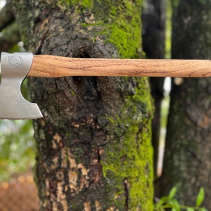May include: A small, silver axe with a wooden handle. The axe has a curved blade and a small, decorative design on the head.