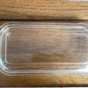 May include: A clear glass rectangular butter dish with a lid.