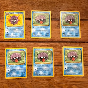 May include: A set of ten Pokemon trading cards featuring the Pokemon Shellder and Cloyster. The cards are in good condition and have a blue, green, and white color scheme. The cards feature the text "Shellder" and "Cloyster" along with the Pokemon's stats and abilities.