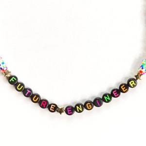 May include: A black beaded necklace with gold stars and colourful beads spelling out "FUTURE ENGINEER".