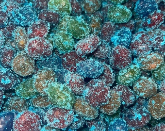 May include: A close-up of a bowl filled with colorful, sugar-coated candies. The candies are a mix of red, green, and blue, and they are all covered in a layer of blue sugar.