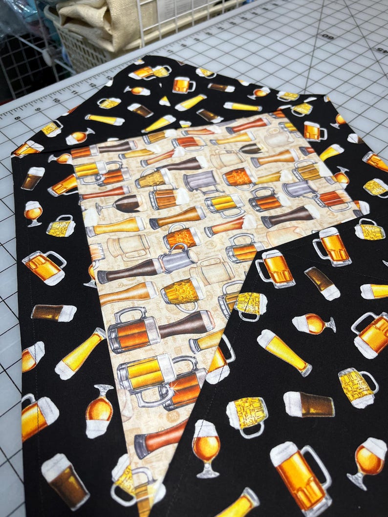 May include: A set of three fabric pieces with beer-themed patterns. The central piece has a beige background with various beer mugs and glasses. The other two pieces have a black background with yellow and brown beer glasses and mugs. The fabrics are likely for crafting or home decor.