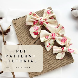 May include: A PDF pattern and tutorial for making a hair bow. The image shows three hair bows made with a cream fabric with pink floral print.