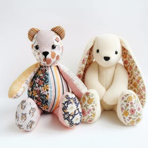 May include: Two handmade plush toys: a bear and a bunny. The bear has a patchwork design with floral and striped patterns in pink, orange, and navy. The bunny is white with floral-patterned ears and feet. Both are sitting.