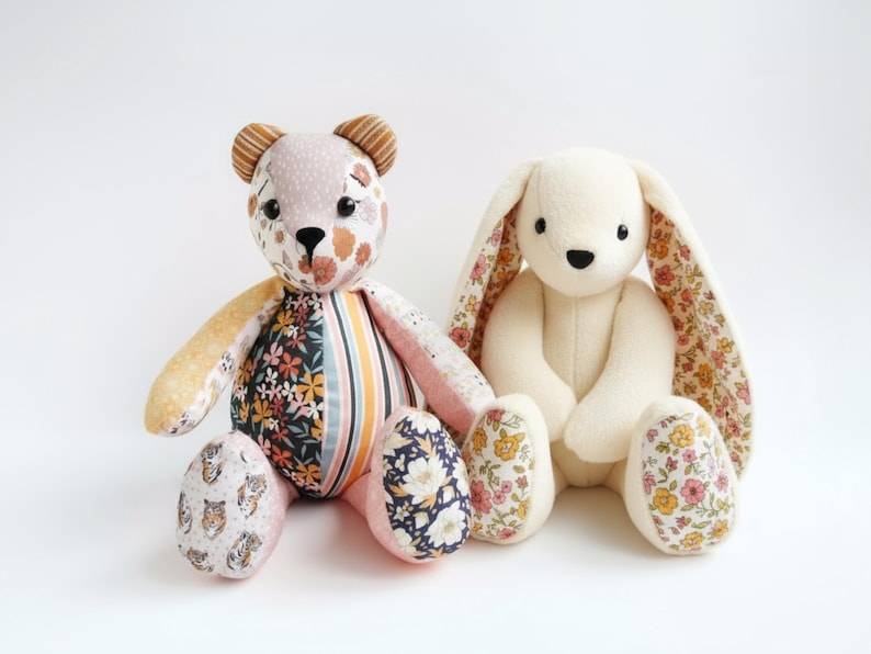 May include: Two handmade plush toys: a bear and a bunny. The bear has a patchwork design with floral and striped patterns in pink, orange, and navy. The bunny is white with floral-patterned ears and feet. Both are sitting.