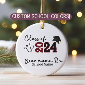 May include: White ceramic ornament with the text "Class of 2024" in red and black lettering. A stethoscope and graduation cap are also included. The text "Your name, RN" and "School Name" are also included.