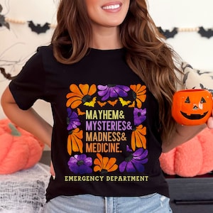 May include: Black t-shirt with a floral design and the text "Mayhem & Mysteries & Madness & Medicine. Emergency Department".