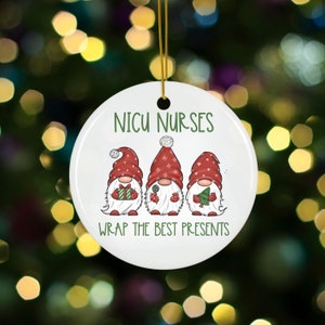 May include: White ceramic Christmas ornament with three gnomes wearing red hats and holding gifts. The ornament reads "NICU NURSES WRAP THE BEST PRESENTS".