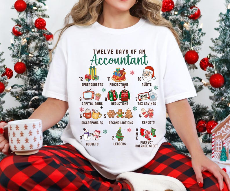 May include: White t-shirt with a Christmas-themed design featuring the text "Twelve Days of an Accountant" and illustrations of gifts, decorations, and other items related to accounting.