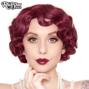 May include: A woman wearing a burgundy wig with finger waves. The wig is styled in a classic vintage look. The image includes the text "RockStar Wigs" in a stylized font. The woman is wearing a pearl necklace and has dark red lipstick.