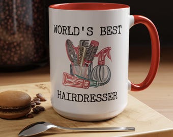 Puede incluir: Taza de cerámica blanca con borde y asa rojos. La taza tiene un gráfico negro de herramientas de peluquería y el texto "WORLD'S BEST HAIRDRESSER".