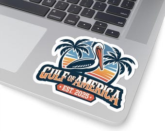 May include: A white sticker with a colorful illustration of a pelican standing on a beach with palm trees. The text "GULF OF AMERICA + EST. 2025+ " is written in a vintage style font.