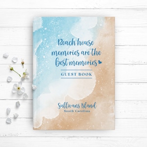 May include: A blue and tan watercolor guest book with the text "Beach house memories are the best memories" and "GUEST BOOK" in blue text. The bottom of the book says "Sullivans Island South Carolina" in blue text.