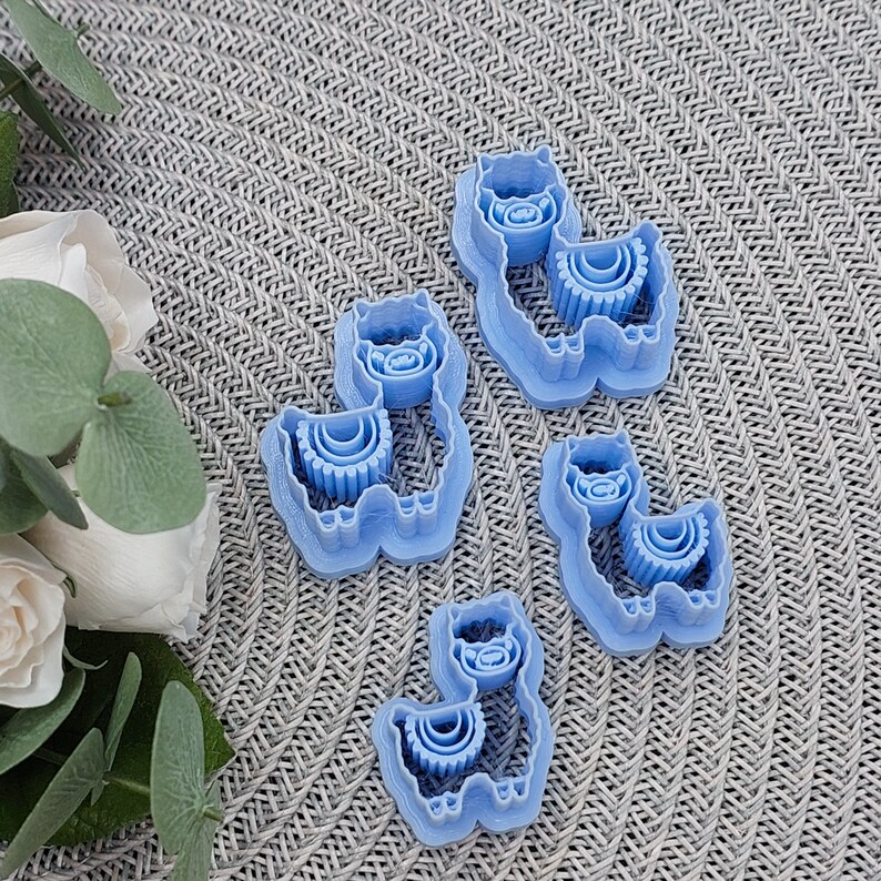 May include: Four blue plastic cookie cutters shaped like llamas. Each llama has a layered fluffy mane and tail.