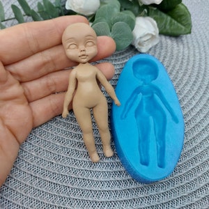 Puede incluir: Un molde de silicona para hacer una peque&ntilde;a figura de mu&ntilde;eca. El molde es azul y tiene la forma de una figura de mu&ntilde;eca en el interior. Se muestra una figura de mu&ntilde;eca terminada junto al molde.