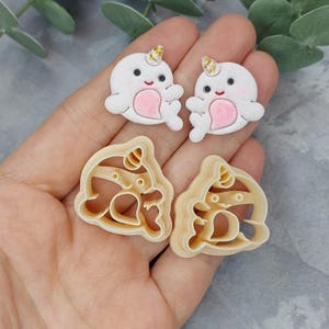 May include: Two white narwhal cookie cutters with gold glitter horns and pink accents. Two beige narwhal cookie cutters with gold glitter horns and pink accents.