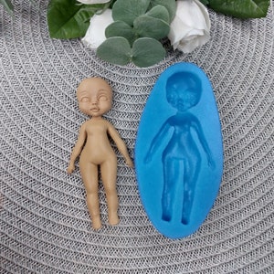 Puede incluir: Un molde de silicona para hacer una figura de mu&ntilde;eca. El molde es azul y tiene la forma de una figura de mu&ntilde;eca. Una figura de mu&ntilde;eca marr&oacute;n est&aacute; al lado del molde.