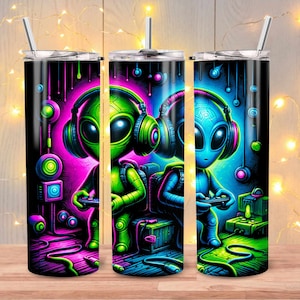May include: Three stainless steel tumblers with a black background and a colorful graphic of two aliens wearing headphones and playing video games. The aliens are green and blue with neon pink and green accents.