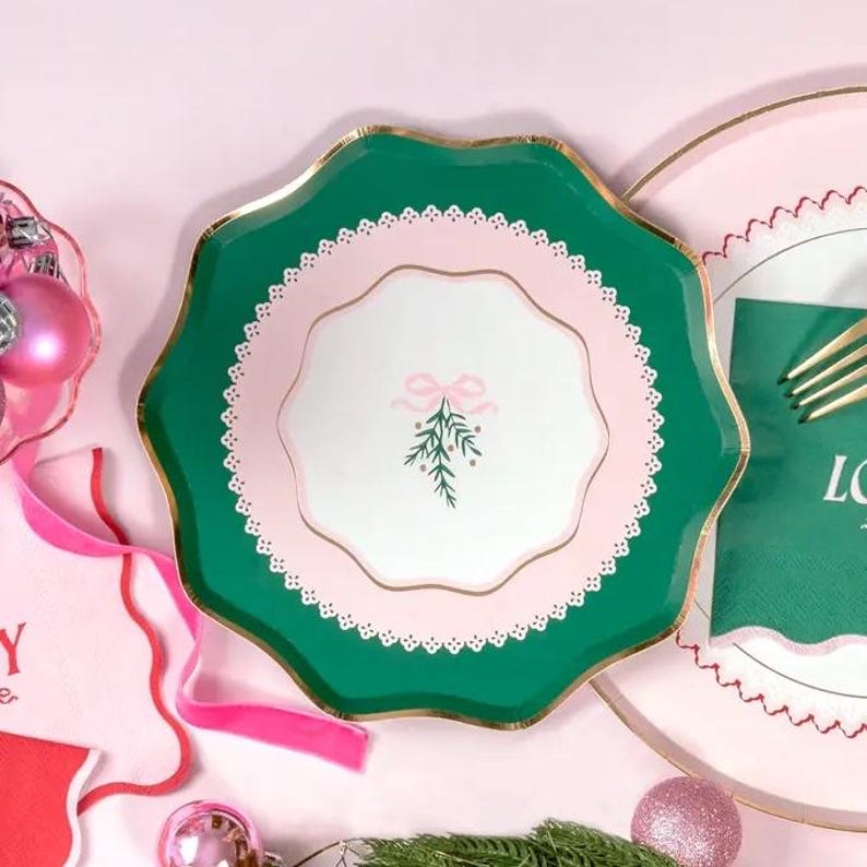Puede incluir: Plato de papel verde y rosa para fiestas con borde festoneado y centro blanco con una rama verde con un lazo rosa.