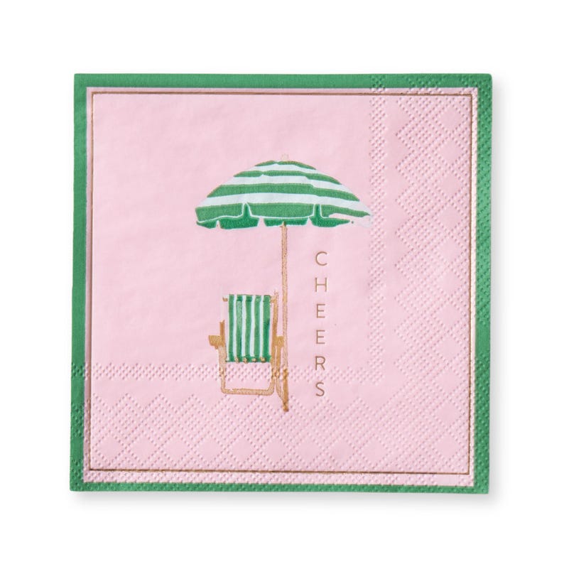 May include: A pink square paper napkin with a green border and gold trim. The napkin features a beach scene with a green and white striped umbrella, a matching chair, and the word "CHEERS" in gold.