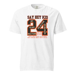 Puede incluir: Una camiseta blanca con un gráfico negro y naranja de un jersey de béisbol con el número 24. El gráfico incluye el texto "Say Hey Kid", "Roy", "2X MVP", "Hall of Fame", "24X All Star", "12X Gold Glove", "1948-1973", "1931-2024", "301 BA 3293 H 525 28 141 38 660 HR" y "3005 G 1909 RBI 2068 R 339 SB 557 SLG".