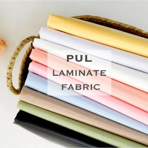 May include: A stack of different colored fabric swatches in a wicker basket. The fabric is labeled "PUL Laminate Fabric".