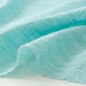 May include: Close-up of a light blue fabric with a textured surface.