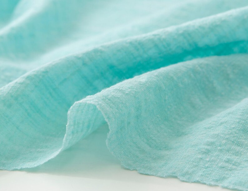 May include: Close-up of a light blue fabric with a textured surface.