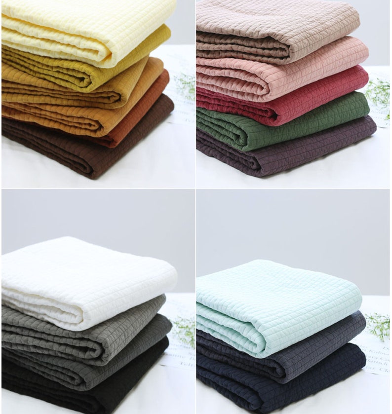 Puede incluir: Una pila de ocho muestras de tela acolchada en varios colores, incluyendo beige, amarillo, naranja, marr&oacute;n, rosa, rojo, verde y gris. La tela tiene una textura acolchada sutil.