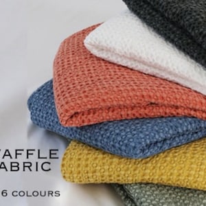 May include: A stack of waffle fabric in six colors: coral, blue, yellow, green, white, and gray.  WAFFLE FABRIC IN 6 COLORS.