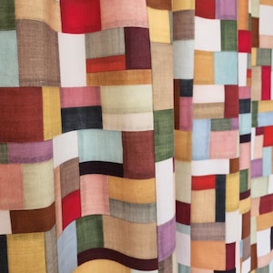 Peut inclure: Un tissu patchwork coloré avec une variété de couleurs et de textures, notamment le rouge, le bleu, le vert, le jaune et le brun. Le tissu est disposé selon un motif géométrique de carrés et de rectangles.
