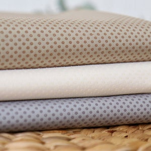 May include: Three fabric swatches with a polka dot pattern. The top swatch is brown with tan dots, the middle swatch is white with white dots, and the bottom swatch is gray with gray dots.