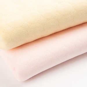 Puede incluir: Dos piezas de tela dobladas, una de color amarillo pálido y otra de color rosa pálido, con una superficie texturizada.