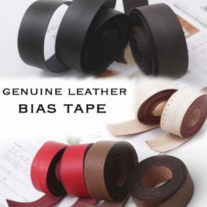 May include: Assortment of leather bias tape rolls in various colours, including black, brown, red, and white. The tape is genuine leather and is ideal for sewing and crafting projects. The image also includes the text "GENUINE LEATHER BIAS TAPE".