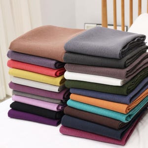 Peut inclure: Un assortiment d'échantillons de tissu de différentes couleurs, dont le marron, le gris, le rouge, le jaune, le blanc, le vert, le bleu, l'orange, le turquoise, le marron, le bleu marine et le bordeaux. Le tissu est doux et texturé.