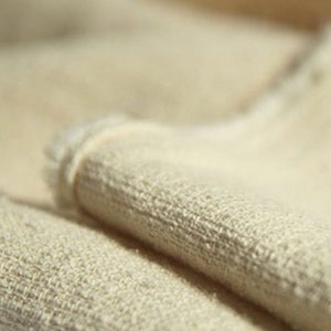 May include: Close-up of a folded piece of off-white linen fabric with a textured weave.