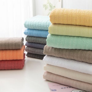 May include: A stack of 10 different colored fabric squares. The fabric is a soft, textured gauze. The colors are light blue, yellow, green, brown, white, beige, and pink.