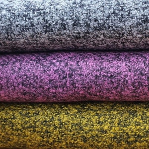 Puede incluir: Tres rollos de tela en diferentes colores: gris con motas negras, rosa con motas negras y amarillo con motas negras.