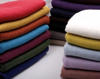 May include: A stack of colorful sweaters in various shades of red, orange, yellow, blue, purple, green, and brown. The sweaters are folded neatly and arranged in a pile.