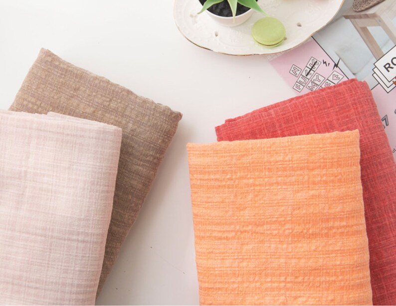 May include: Four fabric swatches in different colors and textures. The swatches are pink, brown, orange, and red. The swatches are arranged in a row on a white surface.