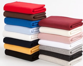 May include: A stack of folded fabric in various colors, including red, brown, blue, white, black, yellow, and gray. The fabric is arranged in two stacks, with one stack taller than the other.