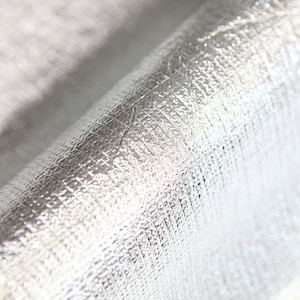 May include: Close-up of a silver, textured, bubble wrap-like material. The material is shiny and reflective.