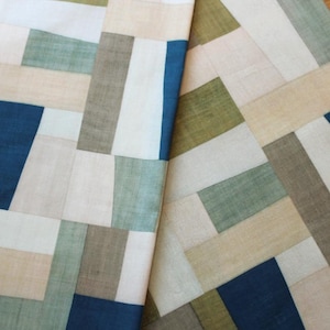 May include: A patchwork fabric with a geometric pattern of beige, brown, blue, and green squares. The fabric is made of a soft, woven material.