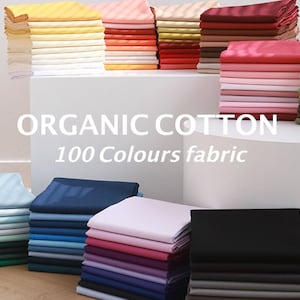 May include: A selection of 100 colours of organic cotton fabric stacked in piles. The fabric is displayed on white surfaces with the text "ORGANIC COTTON 100 Colours fabric".