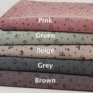 May include: Five fabric swatches stacked on top of each other. The swatches are all patterned with small floral designs. The top swatch is pink, the second is green, the third is beige, the fourth is grey, and the fifth is brown.