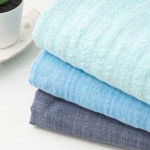 May include: Three pieces of fabric stacked on top of each other. The top piece is a light blue color, the middle piece is a medium blue color, and the bottom piece is a dark blue color.